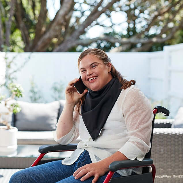women on wheelchair with black bandana smile with phone