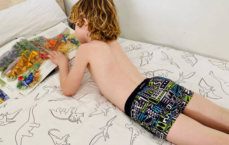 boy reading in bed wearing night training pant graphic pattern back