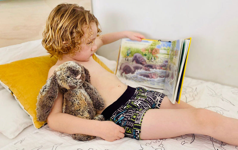 boy reading in bed wearing night training pant graphic pattern