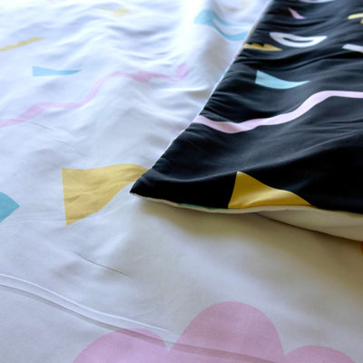 Bright colourful quilt cover fabric.  One side has a whirw background, the other a black background.  Both with colourful shapes.