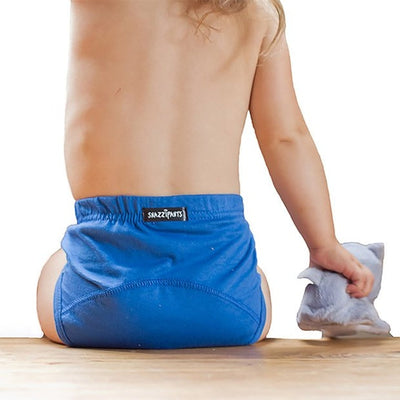 Toddler wear blue training pants sit on bench