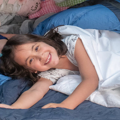 girl smiling lay down in comfort waterproof sleeping bag